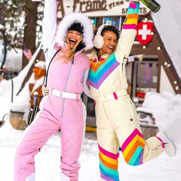 shop women's snow suits - models wearing women's retro rainbow and powder pink snow suits