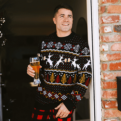 shop christmas clothing - sweaters, onesies, blazers, pajamas, and more - image of man wearing caribrew ugly christmas sweater