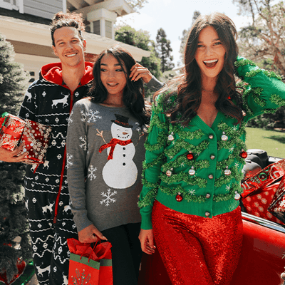 shop christmas - models wearing men's blue reindeer jumpsuit, women's gaudy garland cardigan ugly christmas sweater, and women's sequined snow day ugly christmas sweater