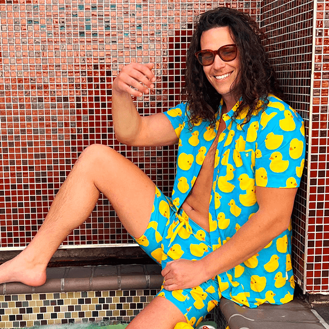 shop vacation - model wearing men's rubber ducky hawaiian shirt and men's rubber ducky stretch swim trunks
