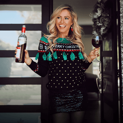 women's christmas outfits - image of woman wearing christmas tree tassel ugly christmas sweater and black sequin skirt