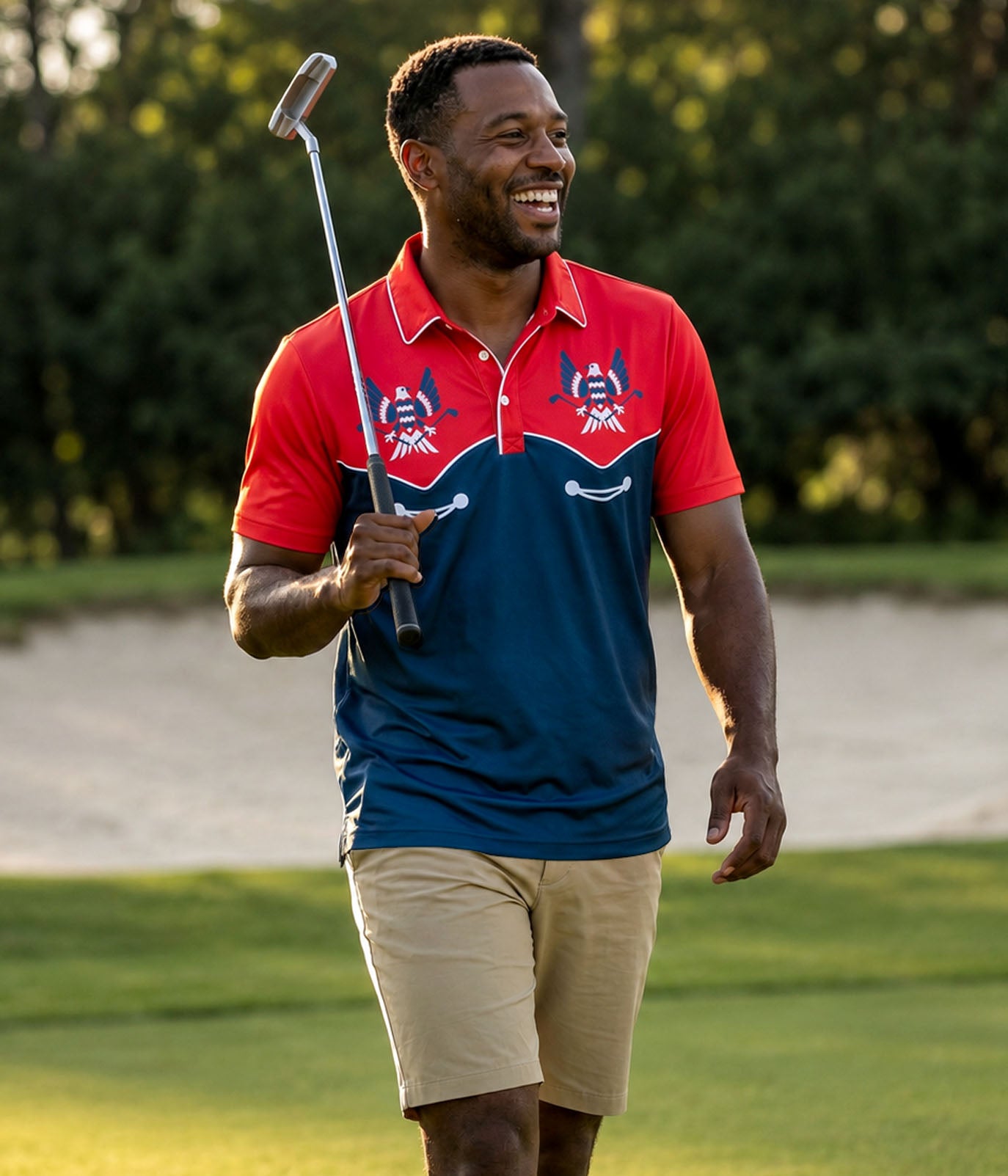 Man in a red and blue polo shirt holding a golf club on a golf course