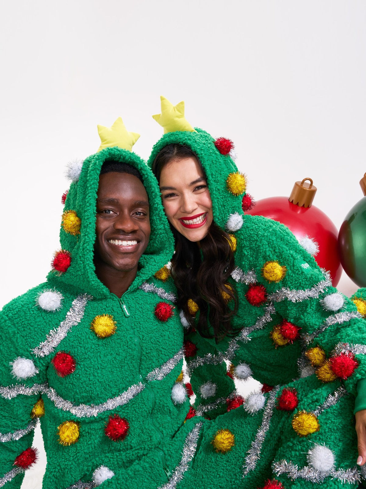 Couple in matching Christmas tree onesies