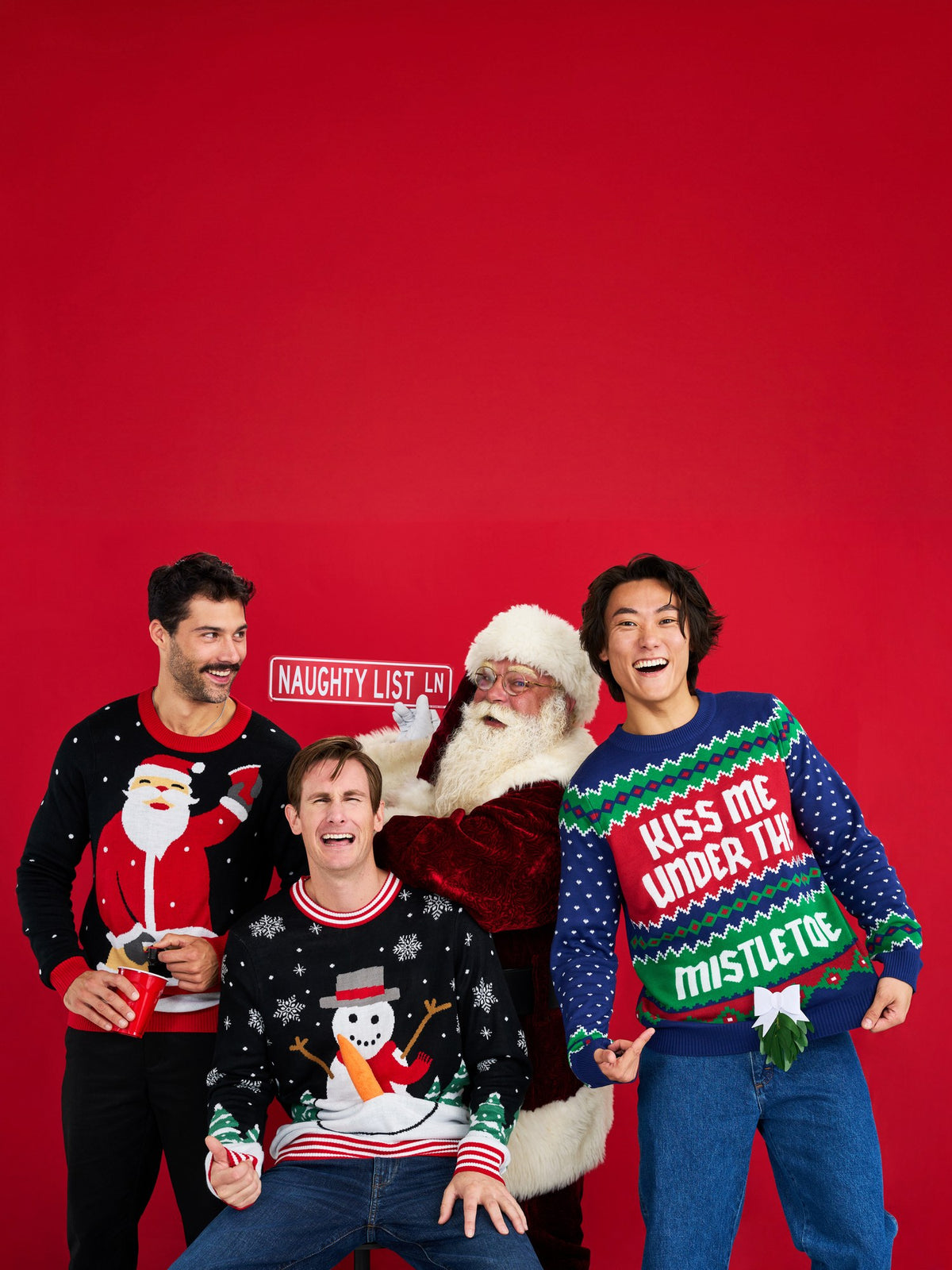 Men in ugly Christmas sweaters posing with Santa